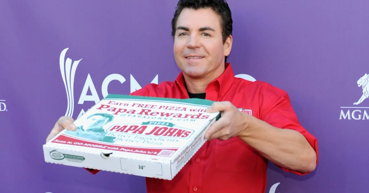 Man in red shirt holding a Papa Rewards pizza box at an event