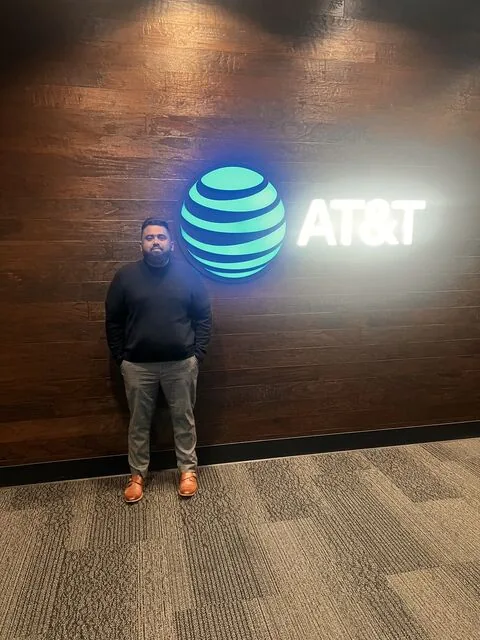 Man standing beside illuminated AT&T logo wall