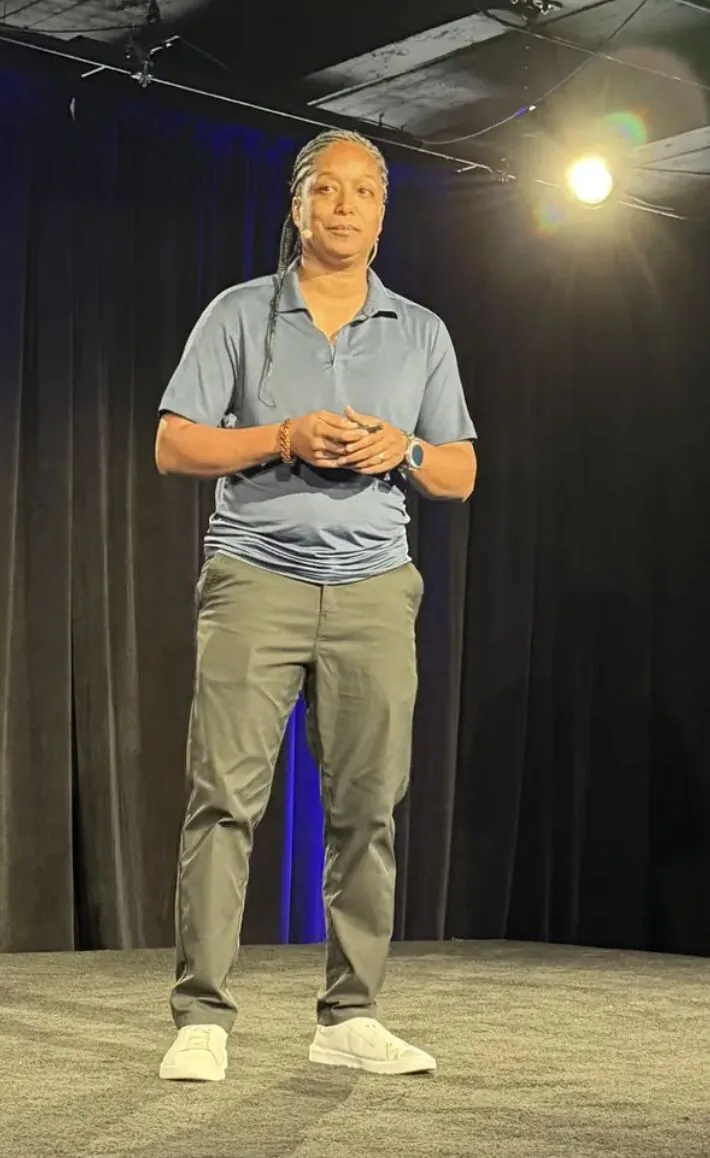 Speaker in light blue shirt presenting on stage