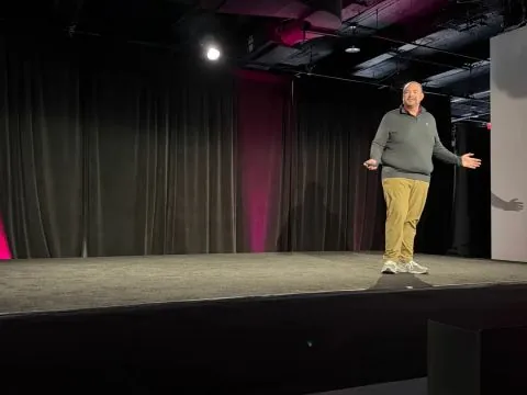 Speaker in grey sweater and khakis presenting on stage