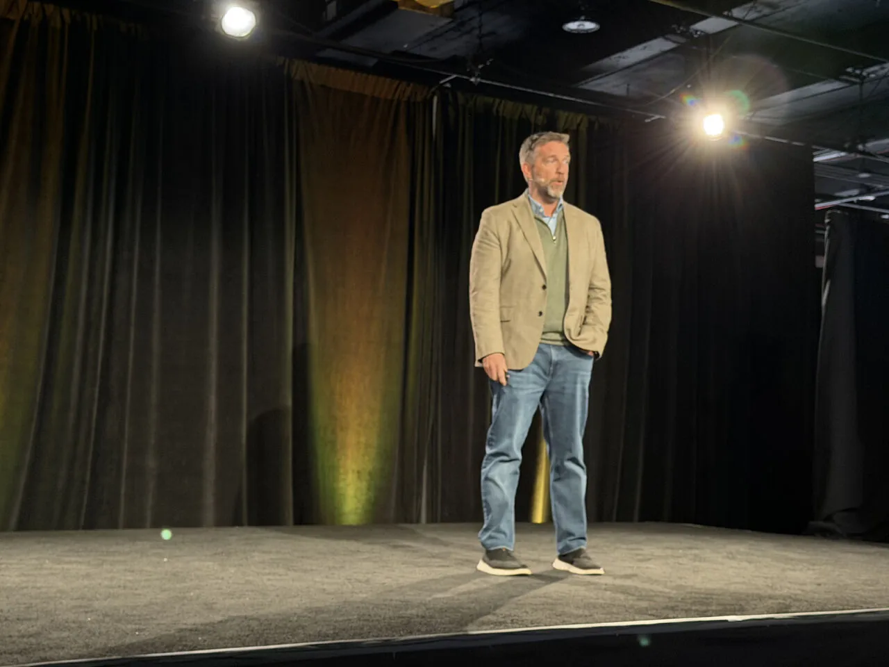 Speaker in tan blazer presenting on stage
