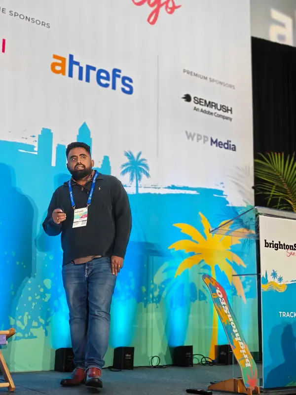Venkata Pagadala mid-talk at brightonSEO San Diego 2026, clicker in hand, in front of the sponsor wall