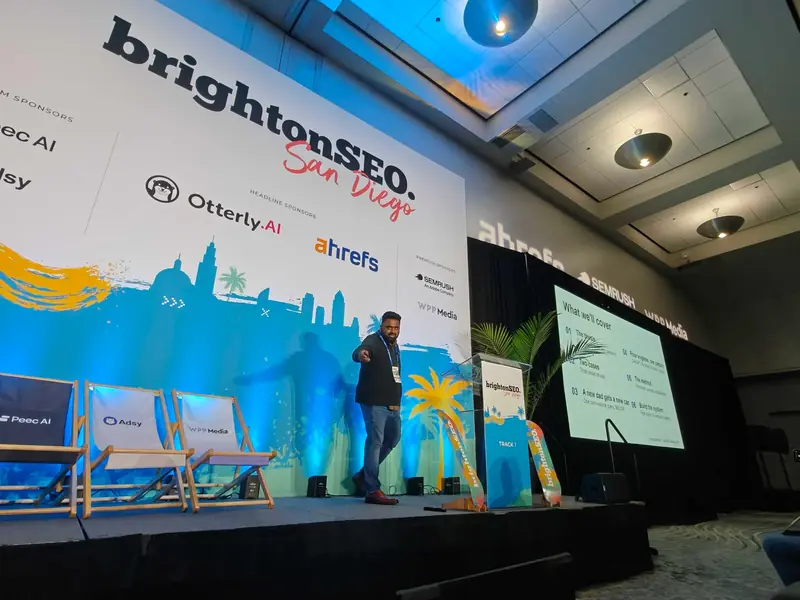 Venkata Pagadala on the Track 1 stage at brightonSEO San Diego 2026, pointing to the audience, with the agenda slide on the screen beside him
