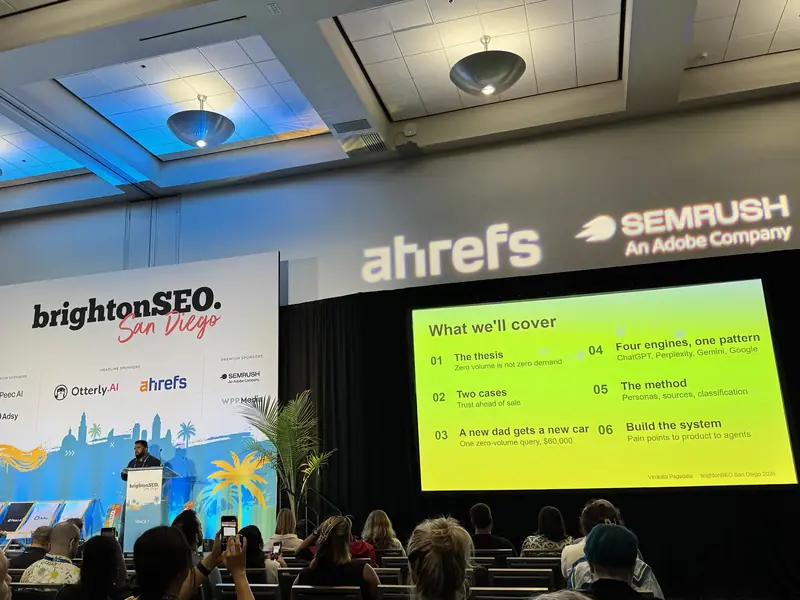 View from the audience: Venkata Pagadala at the Track 1 lectern, the agenda slide on the big screen, and attendees photographing it with their phones